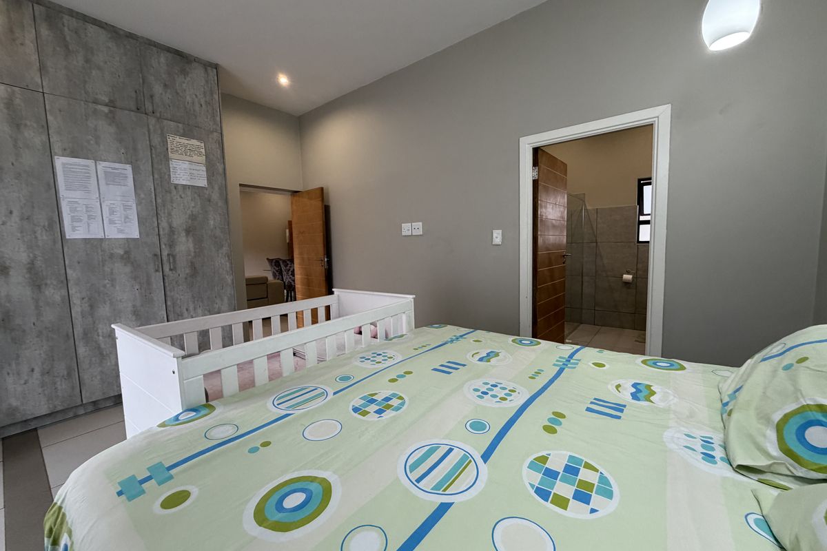 Spacious bedroom featuring modern built-in cupboards, neutral wall finishes, and direct access to an en-suite bathroom.