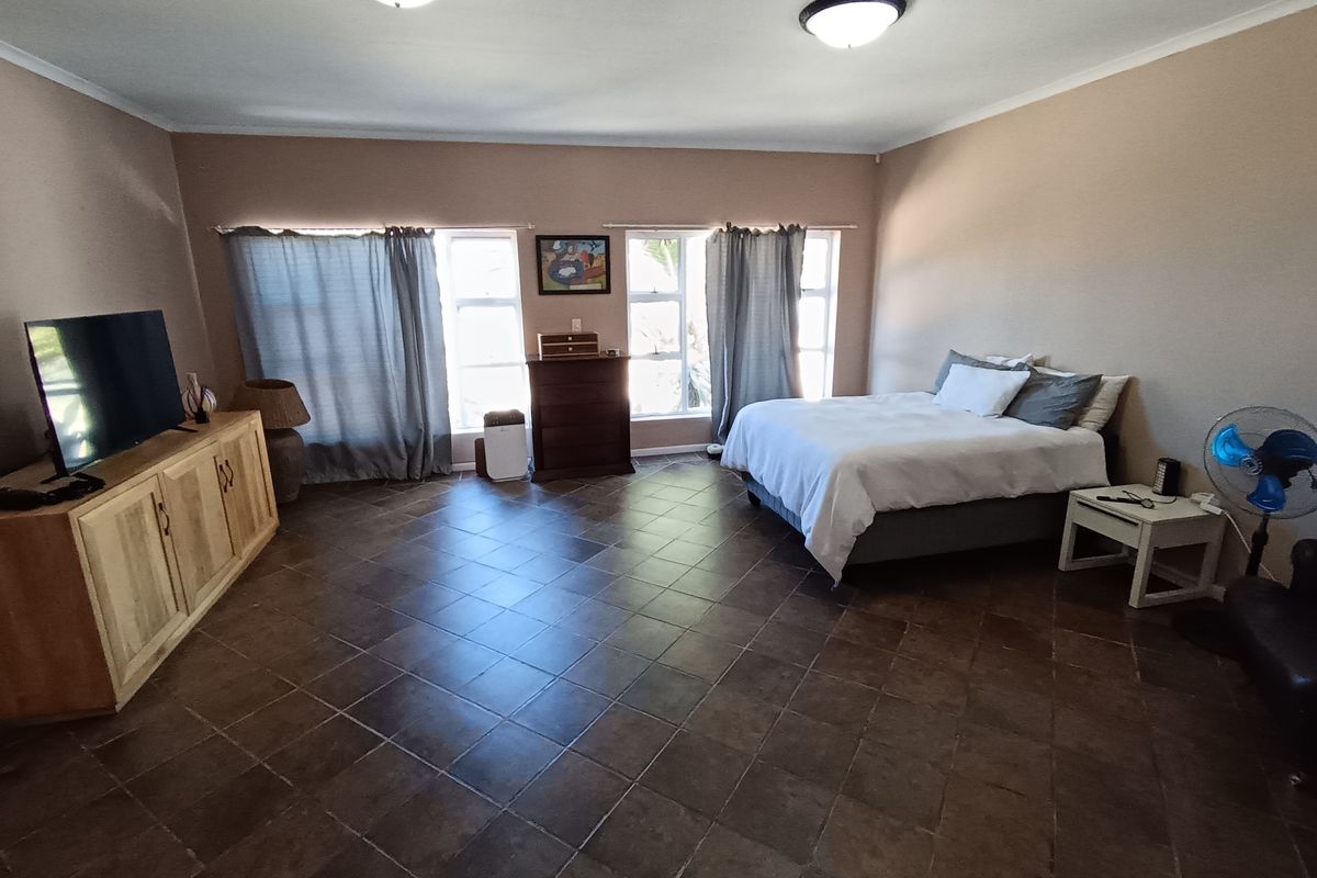 Spacious bedroom featuring dark tiled flooring and dual ceiling light fixtures, offering a neutral canvas for potential interior design updates.