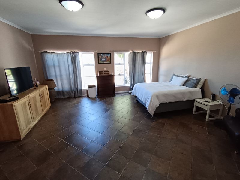 Spacious bedroom featuring dark tiled flooring and dual ceiling light fixtures, offering a neutral canvas for potential interior design updates.