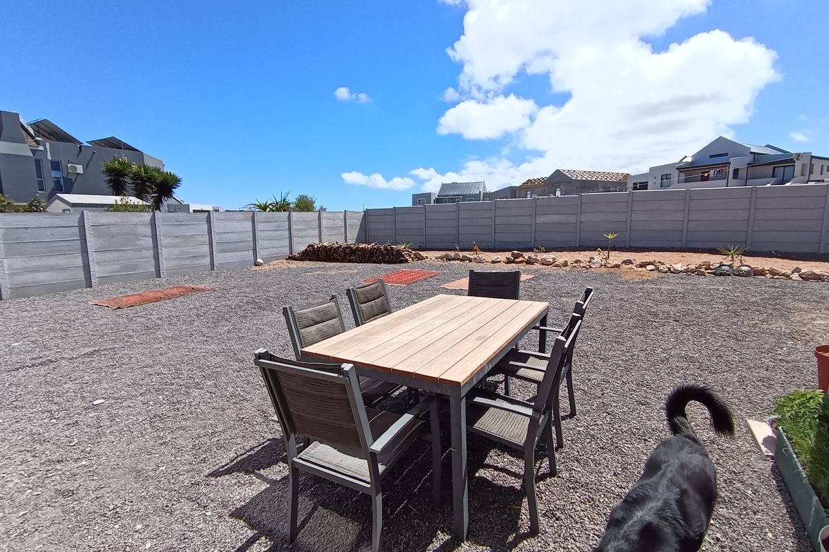 A spacious rear garden area featuring a gravel surface and enclosed by a precast concrete boundary wall.