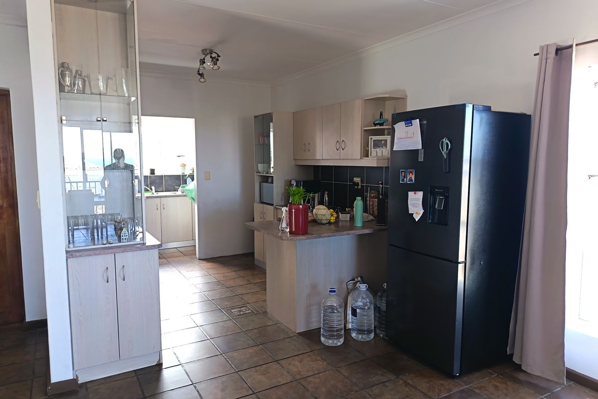 A functional kitchen featuring light wood cabinetry, a breakfast bar, tiled flooring, and a tiled backsplash, with an adjacent scullery area visible.