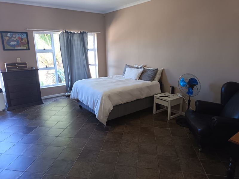 A spacious bedroom featuring large windows for natural light and durable tiled flooring throughout.