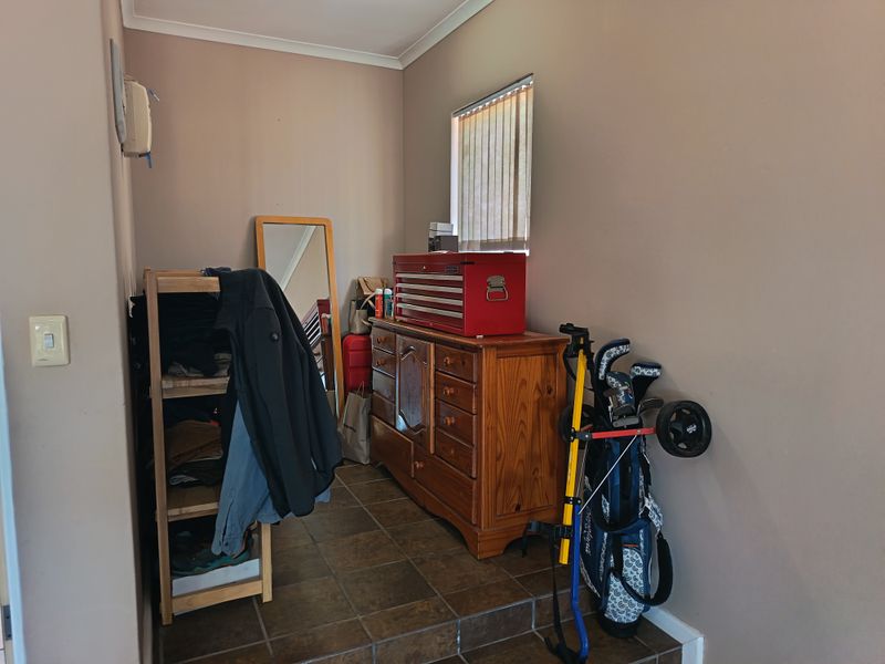 A functional utility space featuring tiled flooring and a window with vertical blinds, currently utilized for storage.