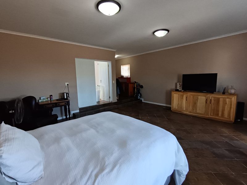 Spacious bedroom featuring tiled flooring, flush mount lighting, and a raised floor section leading to an adjoining room.