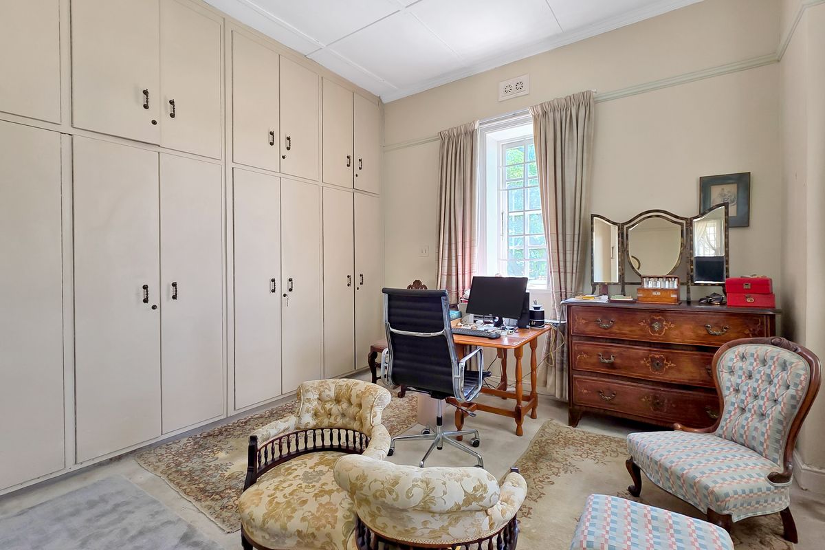 A bedroom featuring extensive built-in floor-to-ceiling cabinetry, a classic sash window, and traditional picture rail detailing.