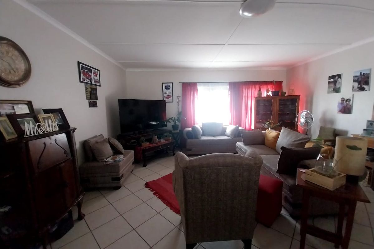 A spacious living room featuring tiled flooring and a large window, providing a comfortable and functional area for relaxation.