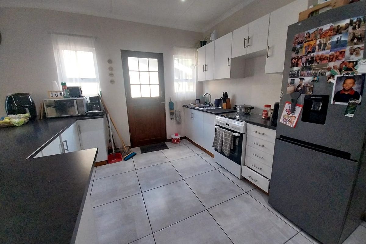 A functional kitchen featuring white cabinetry, dark countertops, tiled flooring, and a built-in stove with an exterior door providing direct access.