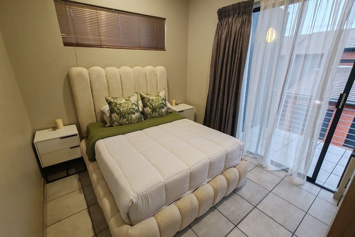 A well-lit bedroom featuring tiled flooring, a horizontal window, and a sliding glass door providing access to an outdoor balcony area.