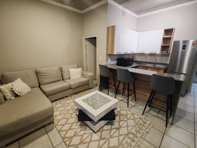 An open-plan living and kitchen area featuring modern cabinetry, a breakfast bar, and tiled flooring, creating a functional and cohesive living space.