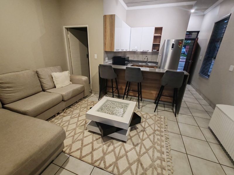 Open plan living area featuring a modern kitchen with breakfast bar, tiled flooring, and neutral wall finishes.