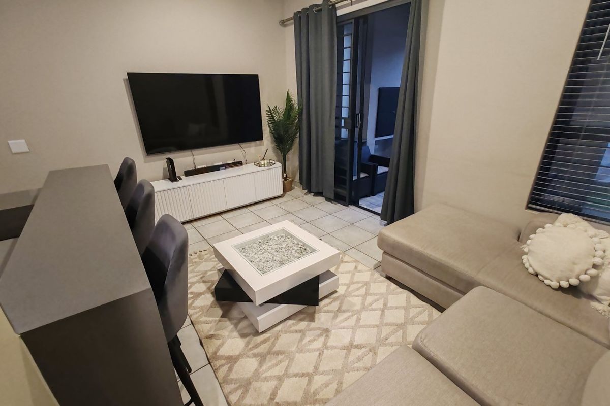 A comfortable living room featuring tiled flooring and a large sliding glass door that provides access to the outdoor patio area.