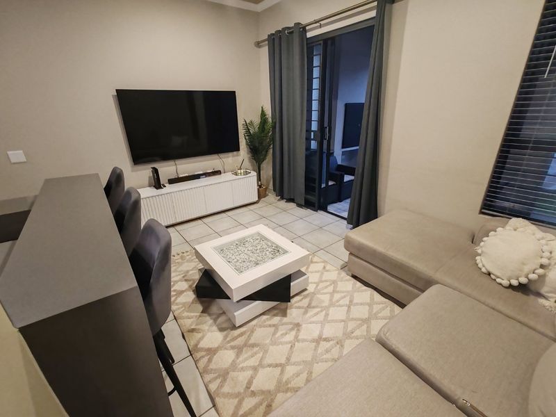 A comfortable living room featuring tiled flooring and a large sliding glass door that provides access to the outdoor patio area.