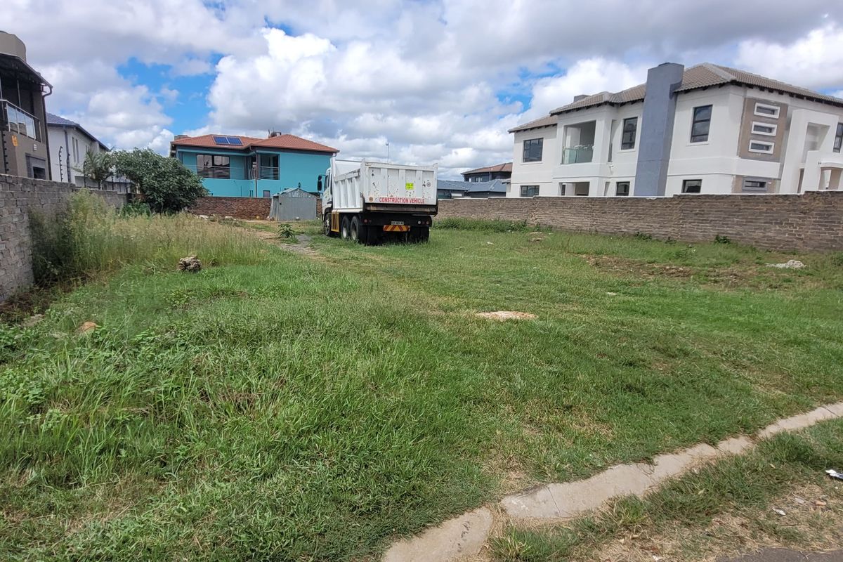 A vacant residential plot featuring perimeter brick walls with electric fencing, offering a clear space ready for development.