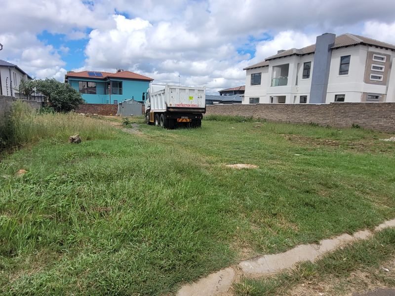A vacant residential plot featuring perimeter brick walls with electric fencing, offering a clear space ready for development.