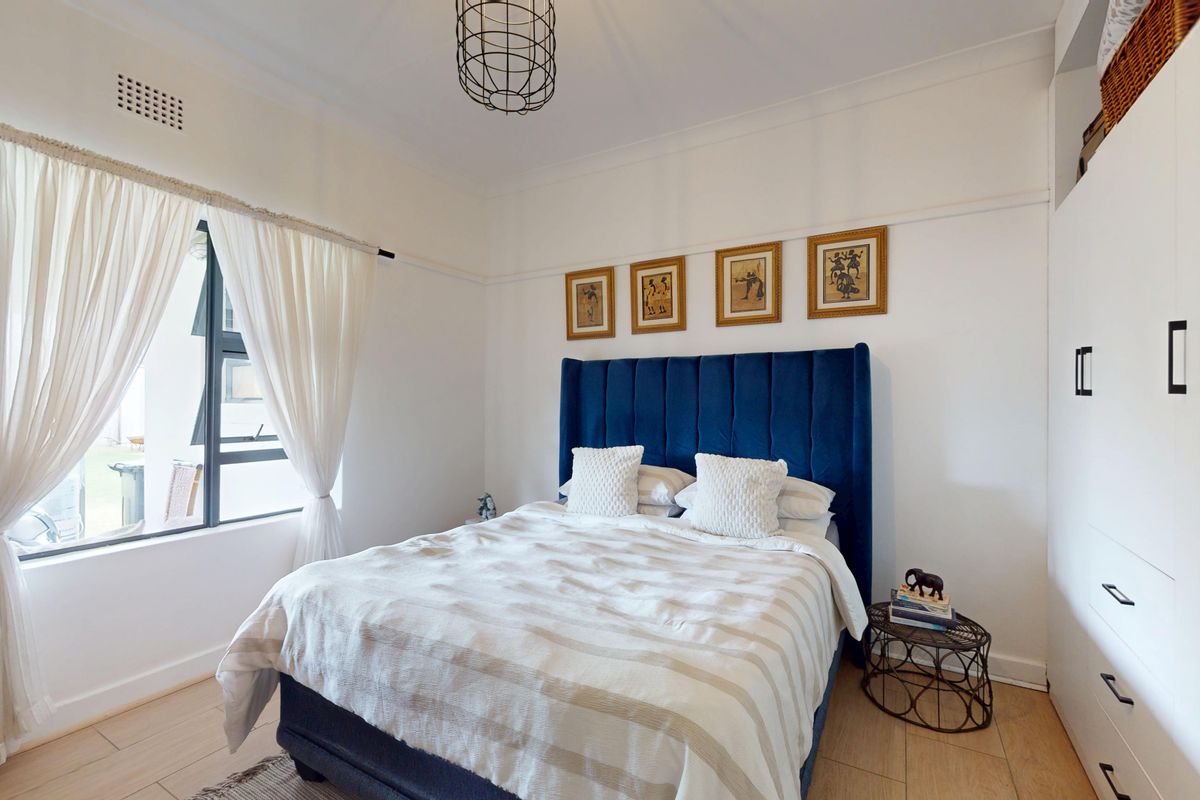 A well-maintained bedroom featuring light wood-look flooring, built-in cabinetry, and a large window allowing for natural light.