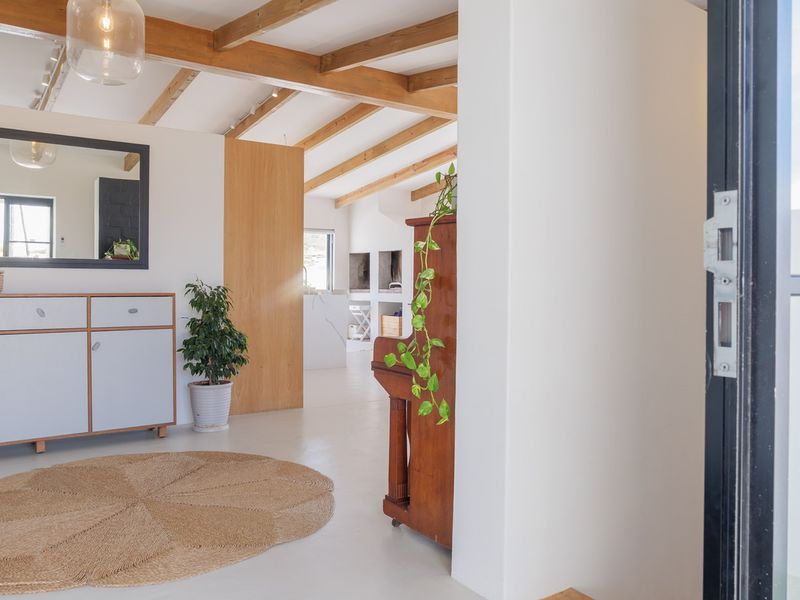 Bright and modern entryway featuring exposed timber ceiling beams, polished concrete flooring, and custom built-in cabinetry, creating a welcoming and airy atmosphere.