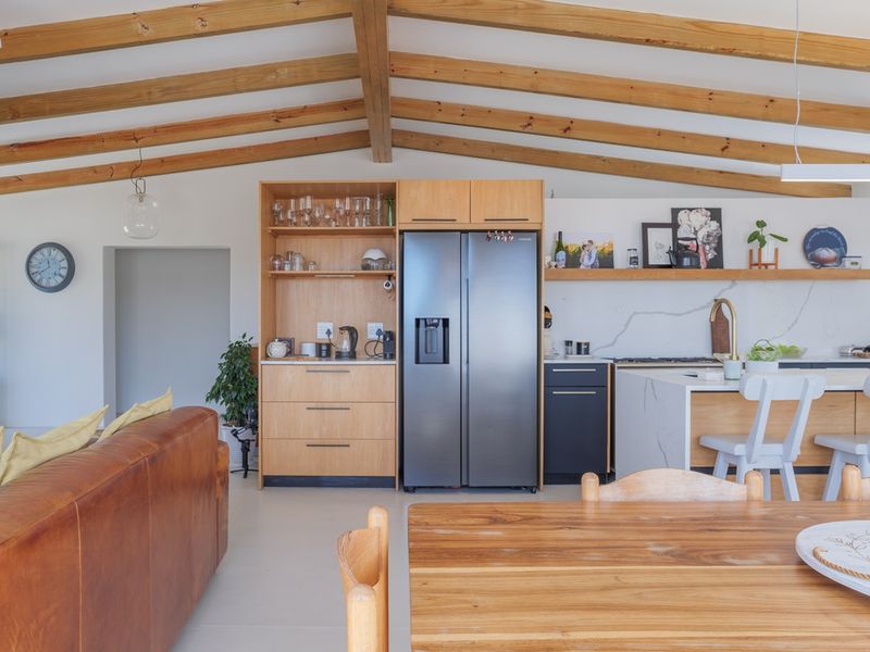 Spacious open-plan living and kitchen area featuring exposed timber ceiling beams, modern cabinetry, a stone-topped island, and high-quality finishes throughout.