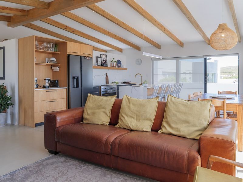 Spacious open-plan living and kitchen area featuring exposed timber ceiling beams, a modern kitchen island, and large sliding doors leading to the exterior.