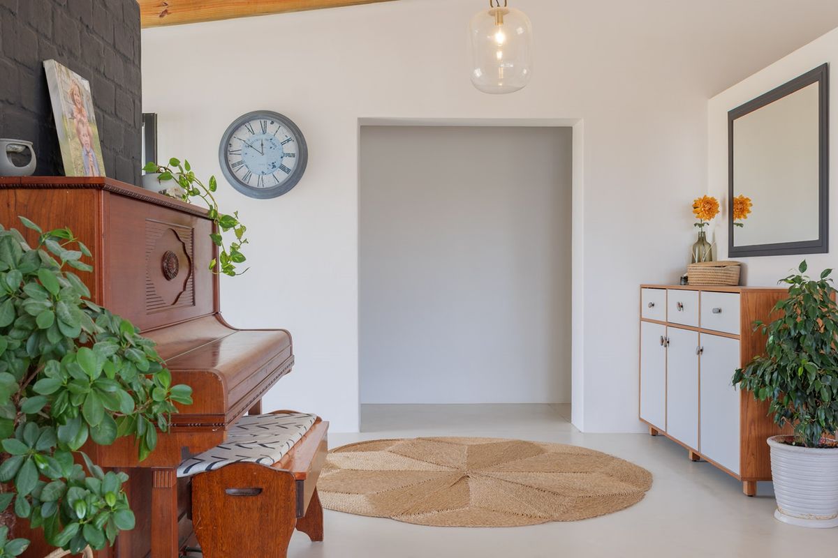 A bright living area featuring a painted brick accent wall, exposed timber ceiling beams, and built-in cabinetry with a clean, modern aesthetic.