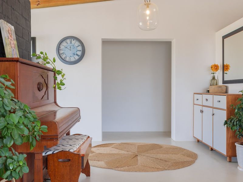 A bright living area featuring a painted brick accent wall, exposed timber ceiling beams, and built-in cabinetry with a clean, modern aesthetic.