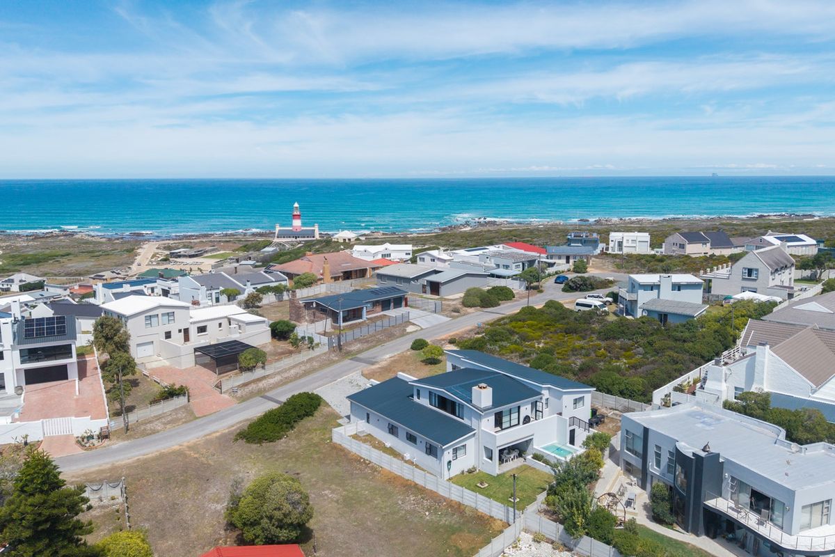 An aerial view of a coastal residential neighbourhood featuring a prominent lighthouse and expansive ocean views.
