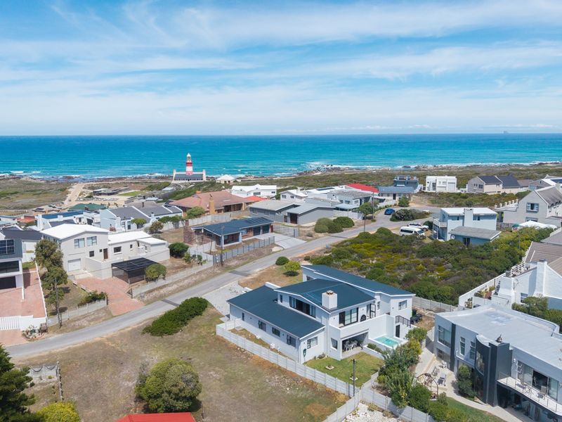 An aerial view of a coastal residential neighbourhood featuring a prominent lighthouse and expansive ocean views.