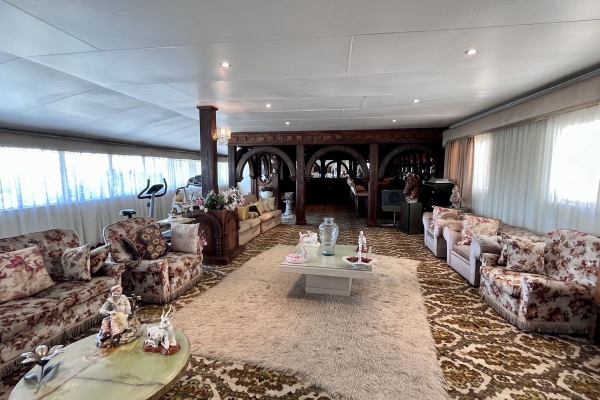 Spacious living room featuring a built-in bar area with decorative archways, recessed lighting, and extensive wall-to-wall carpeting.