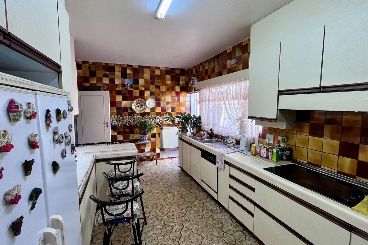 A dated kitchen featuring original cabinetry, tiled splashbacks, and integrated appliances, offering significant potential for a modern renovation and layout update.