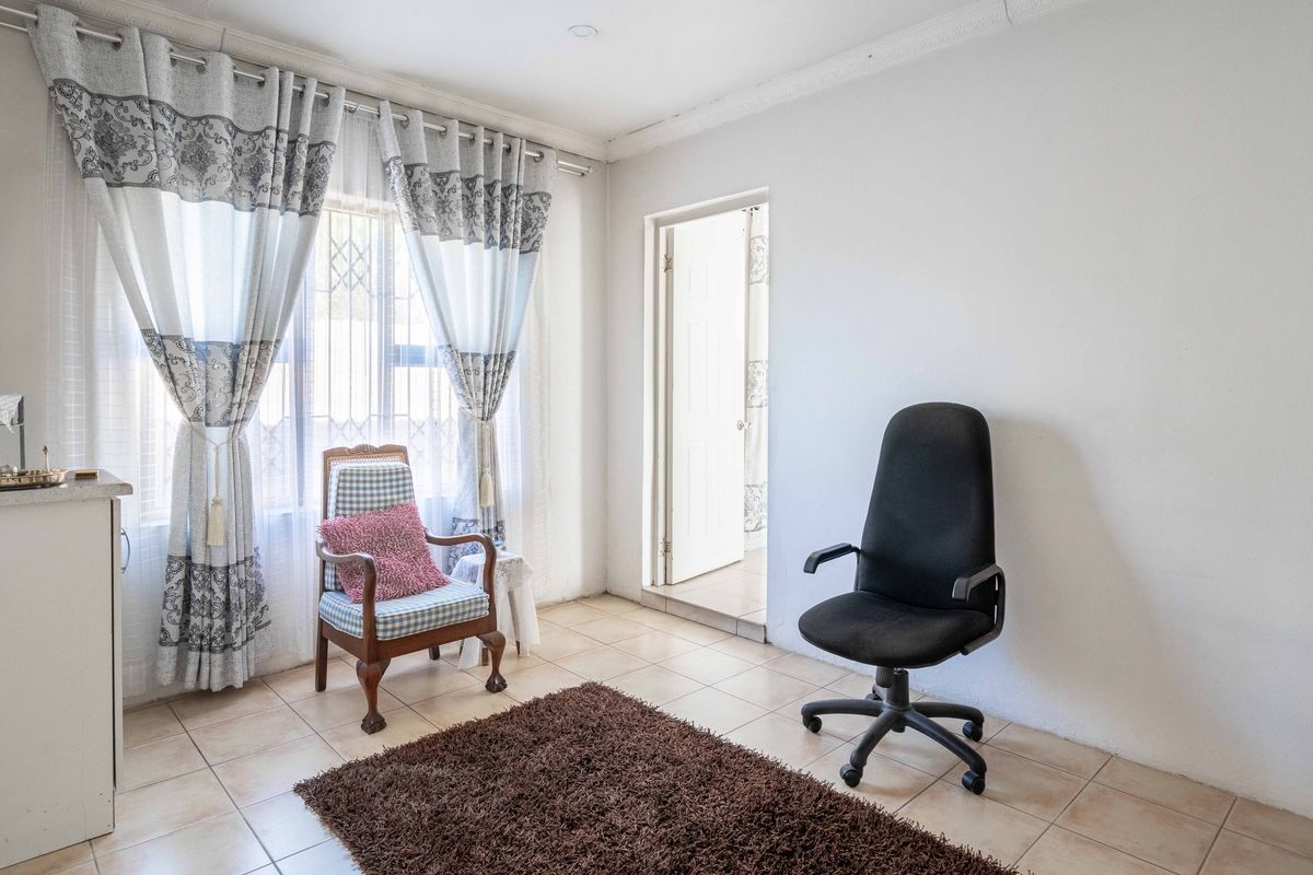 A functional room featuring tiled flooring, decorative curtain rails, and a doorway leading to an adjacent space.