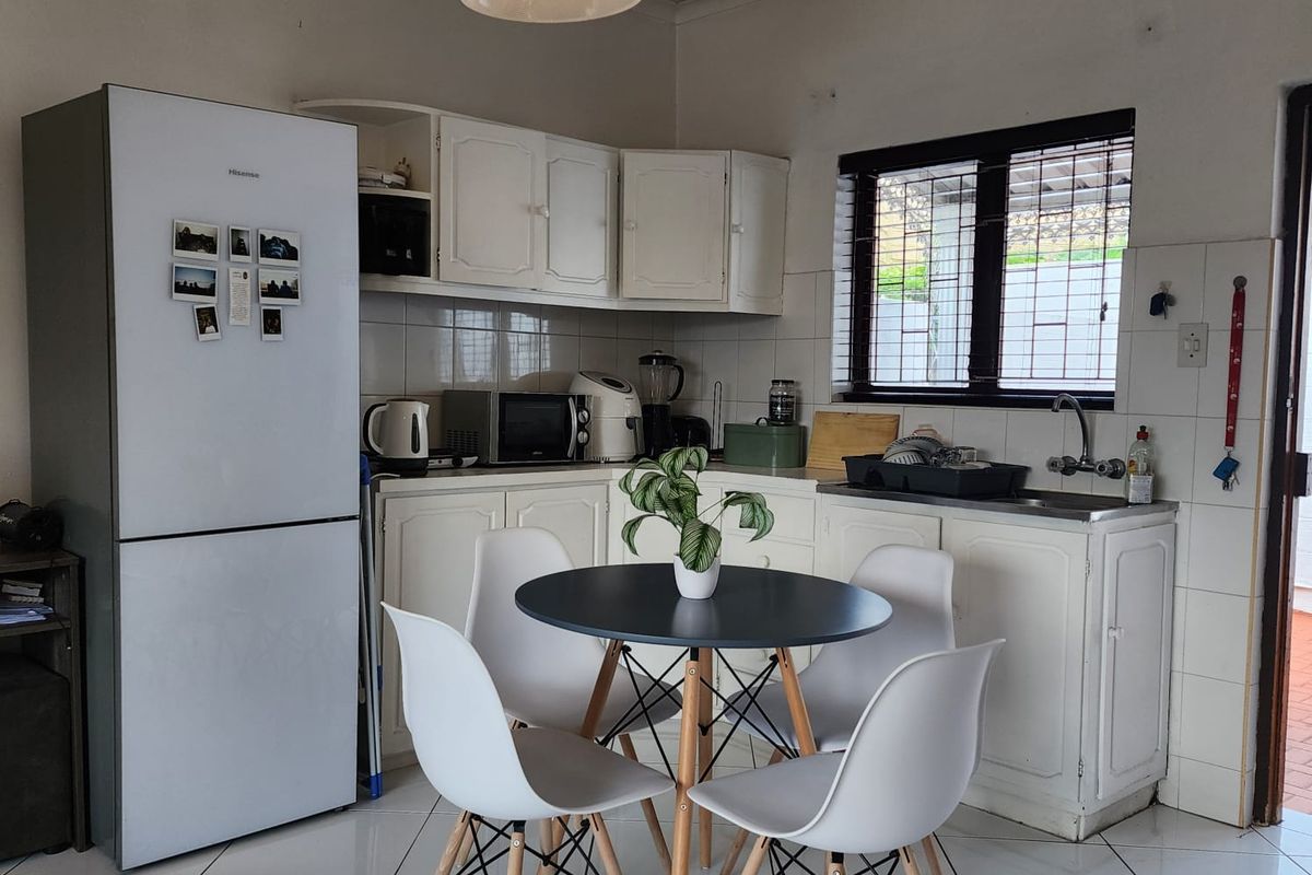 A functional kitchen featuring white cabinetry, tiled flooring, and a stainless steel sink, offering a practical layout for daily meal preparation.