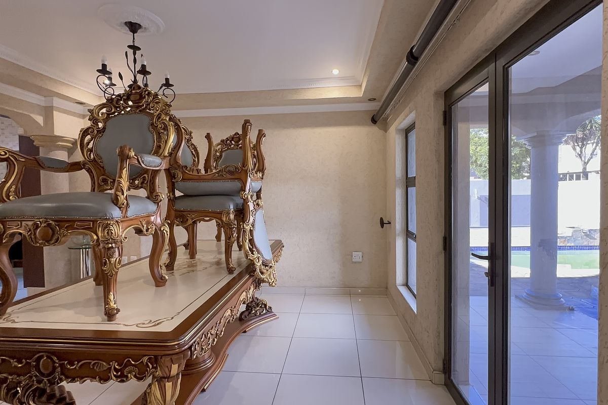 A bright living area featuring tiled flooring, recessed ceiling details, and large aluminium sliding doors providing direct access to the outdoor pool area.