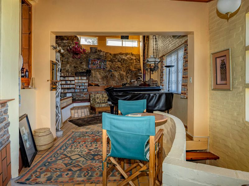 A characterful living room featuring a prominent stone feature wall, exposed brickwork, and traditional terracotta tile flooring with a cozy, rustic aesthetic.
