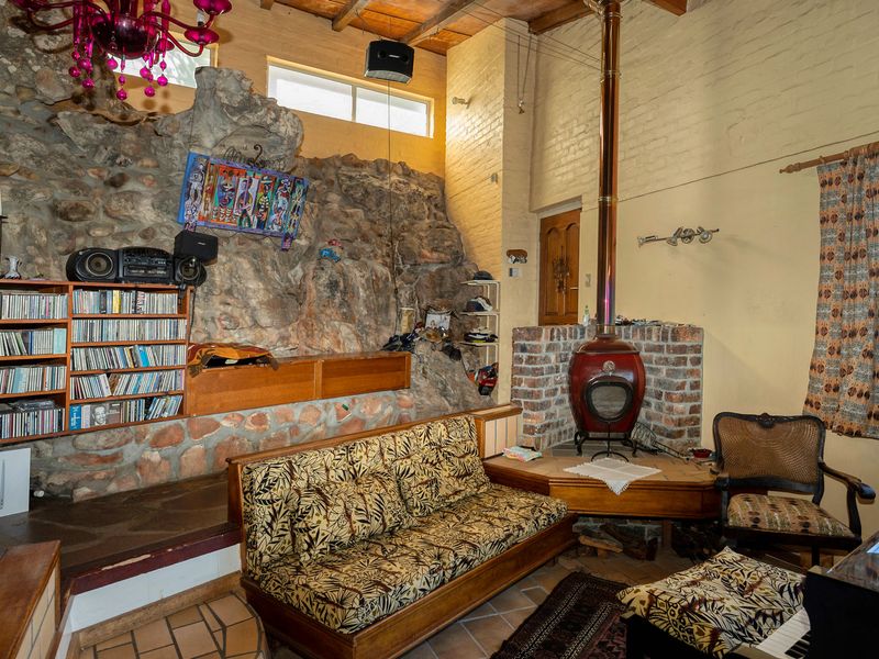 Unique living room featuring a prominent exposed rock feature wall, brick fireplace with a wood-burning stove, and exposed timber ceiling beams.