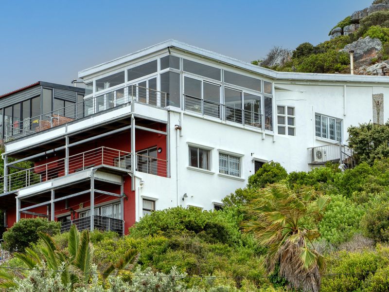 Multi-level residential property featuring extensive glass windows, steel balconies, and terraced hillside landscaping, offering elevated views and a distinct architectural design.