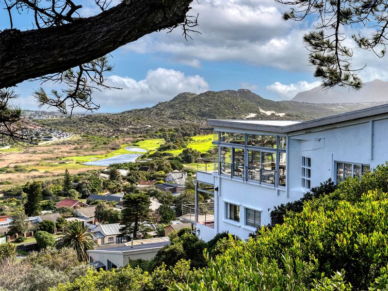 Elevated view of the property showcasing its architectural design, expansive windows, and scenic outlook over the surrounding landscape and golf course.