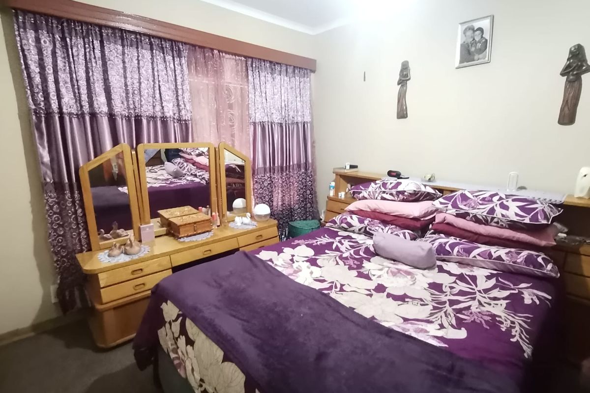 A standard bedroom featuring carpeted flooring and a large window with a curtain rail.