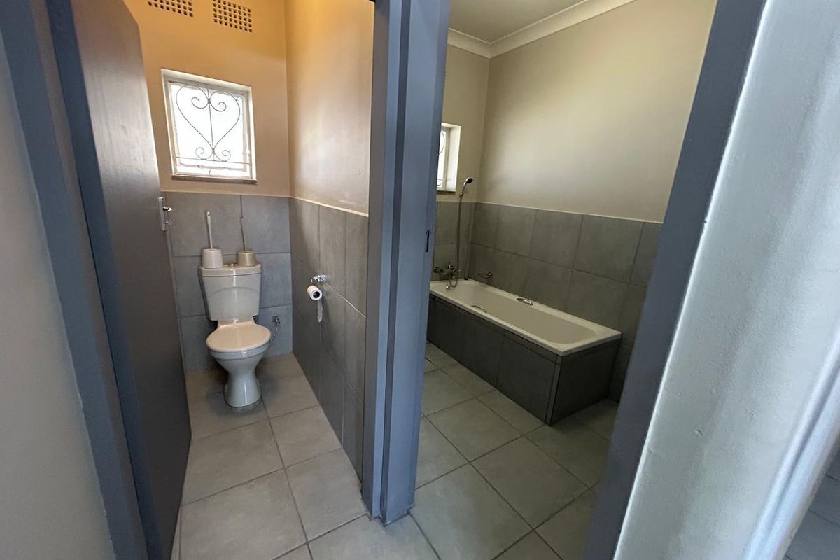 A clean, functional bathroom featuring a separate toilet area and a bathtub with tiled finishes and neutral wall tones.