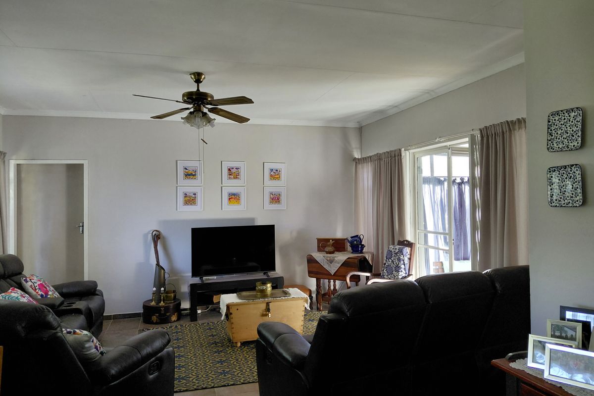 A comfortable living room featuring tiled flooring, a ceiling fan, and a sliding glass door providing access to the outdoor area.