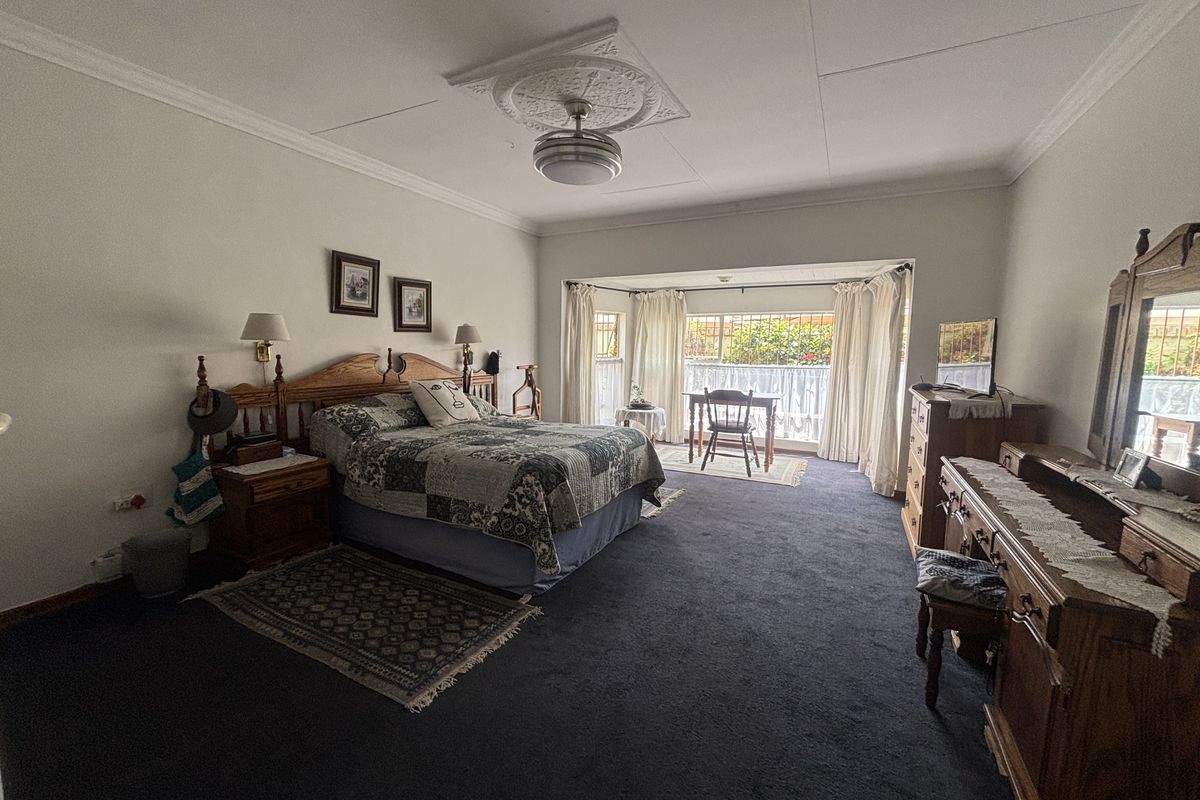 Spacious bedroom featuring a decorative ceiling rose, ceiling fan, and a large bay window that provides ample natural light.