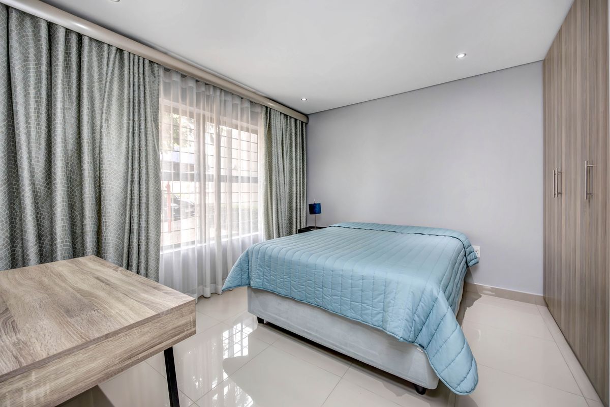 A well-maintained bedroom featuring tiled flooring, recessed ceiling lighting, and built-in wooden cabinetry.