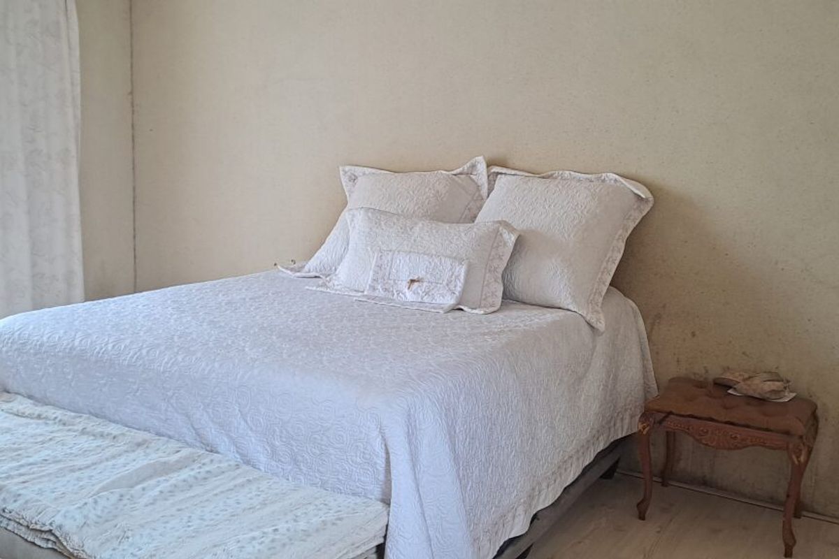 A bedroom featuring neutral walls and natural light, currently requiring cosmetic updates to the wall finishes.