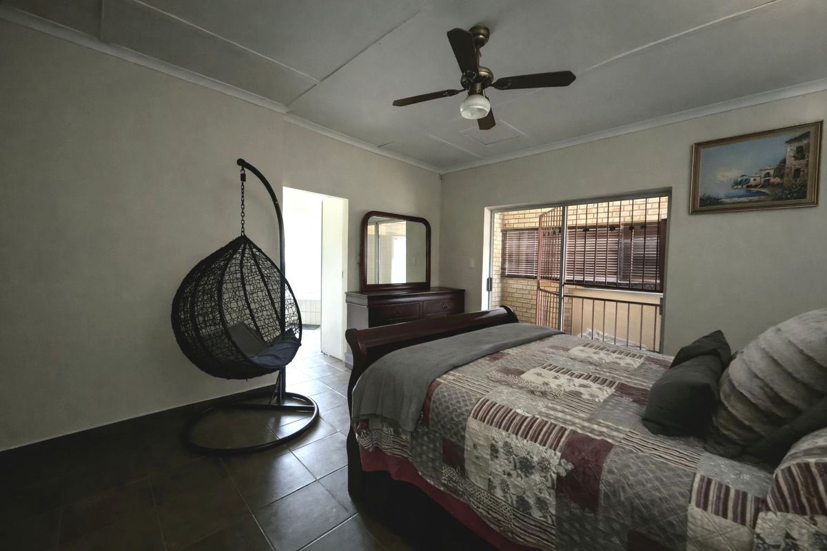 A bedroom featuring tiled flooring, a ceiling fan, and a sliding glass door with a security gate leading to an outdoor area.