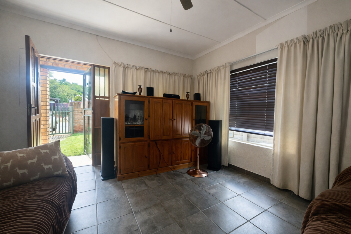 A living room featuring tiled flooring, a ceiling fan, and direct access to the exterior through a security gate.