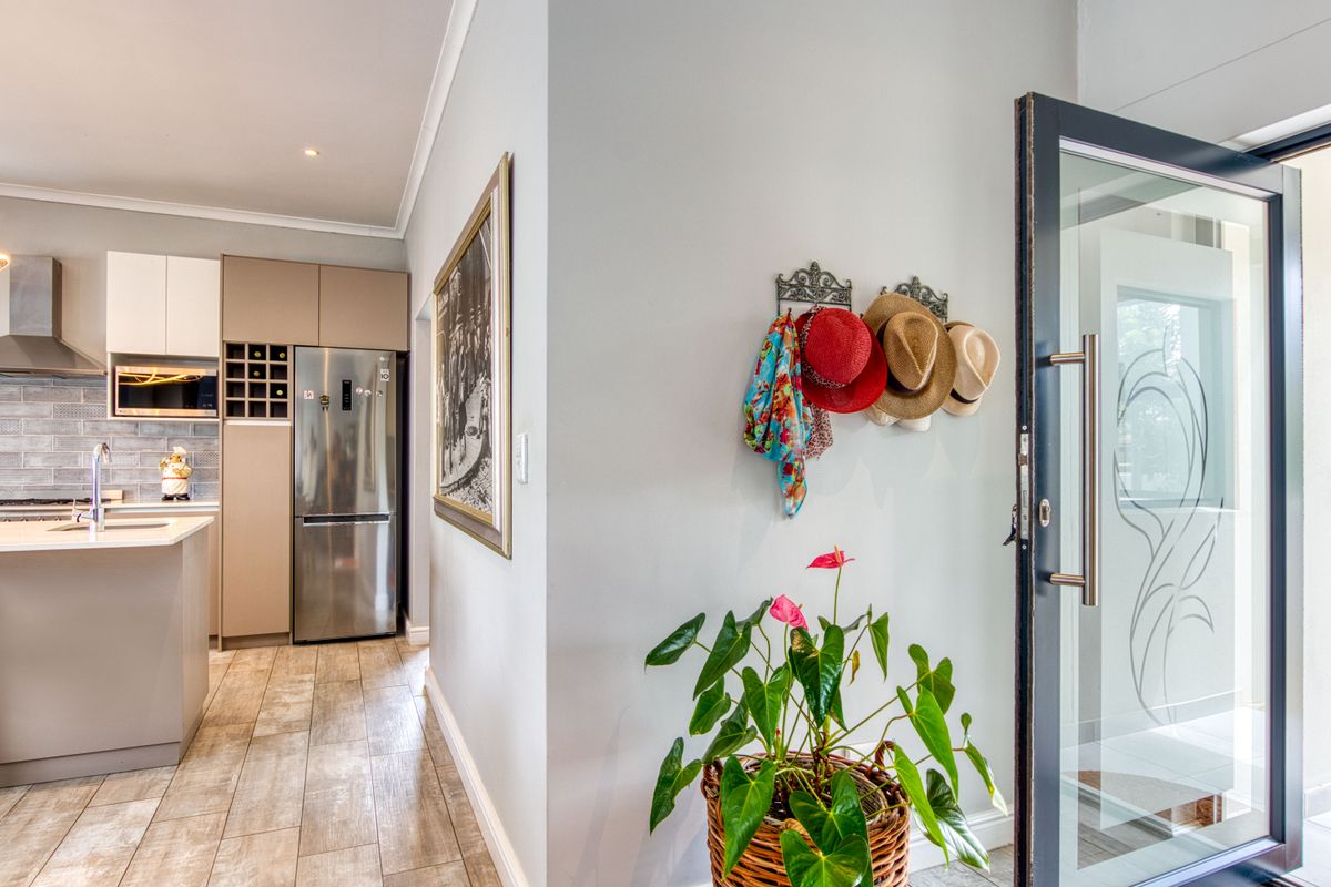 Modern kitchen featuring a central island, built-in appliances, and a wine rack, adjacent to a glass-paneled entrance door with tiled flooring throughout.