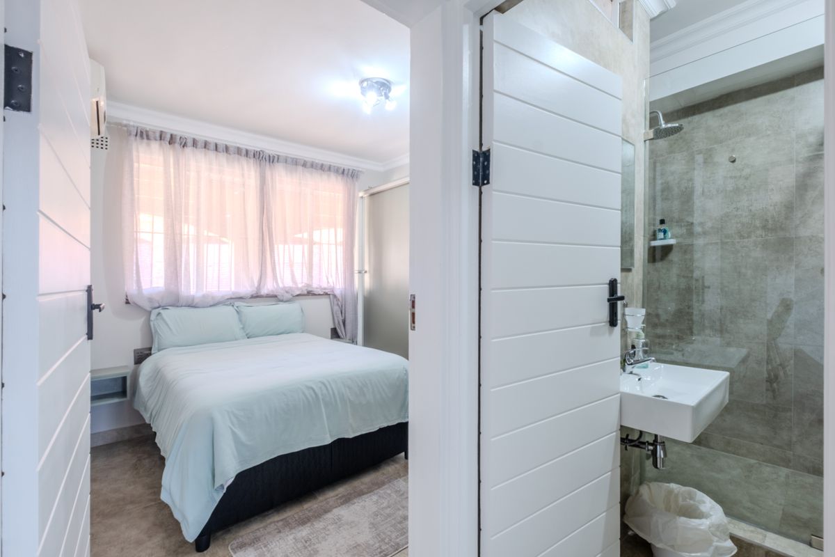 A view from a bathroom doorway looking into a bedroom, featuring modern tiled shower finishes and a clean, functional layout.