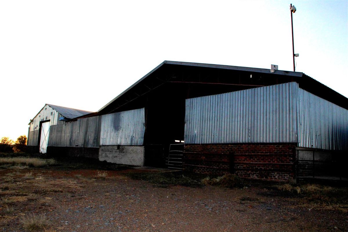 Large agricultural barn structure featuring corrugated metal siding and brick foundation walls, suitable for storage or farm operations.