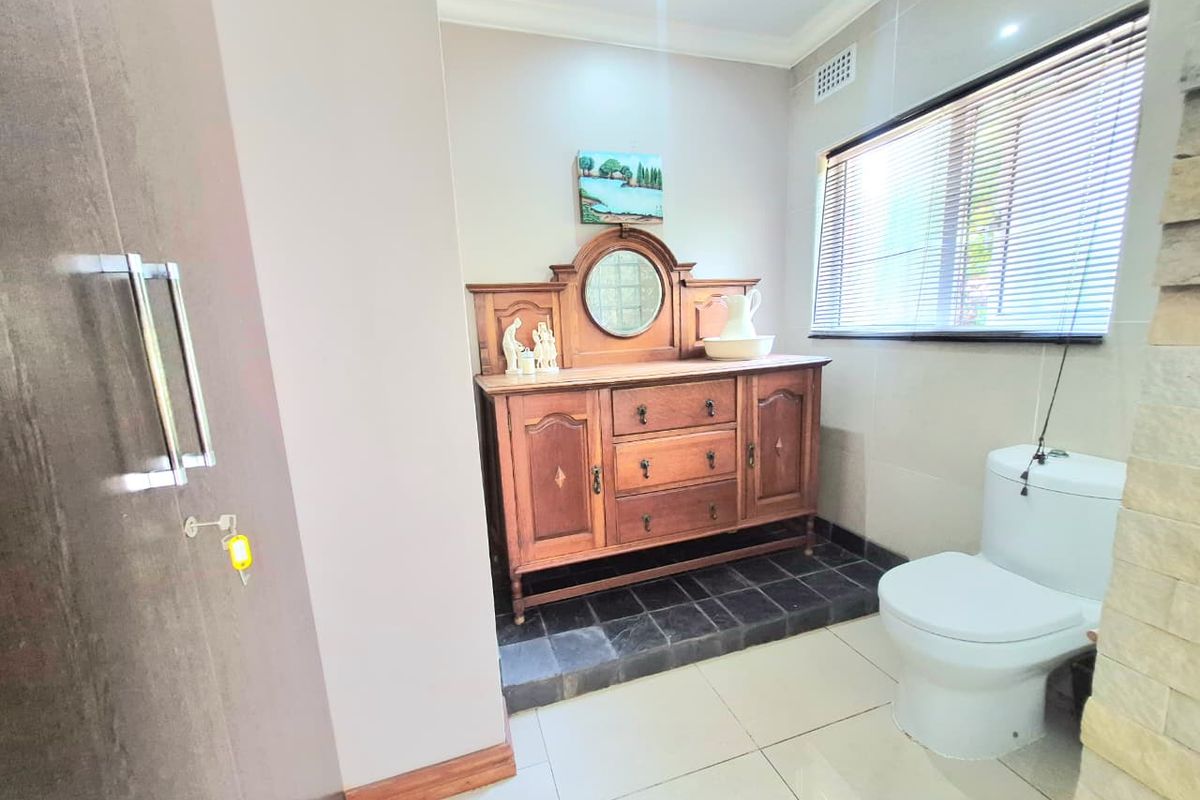 A well-maintained bathroom featuring tiled flooring, a modern toilet, and natural light filtered through venetian blinds.