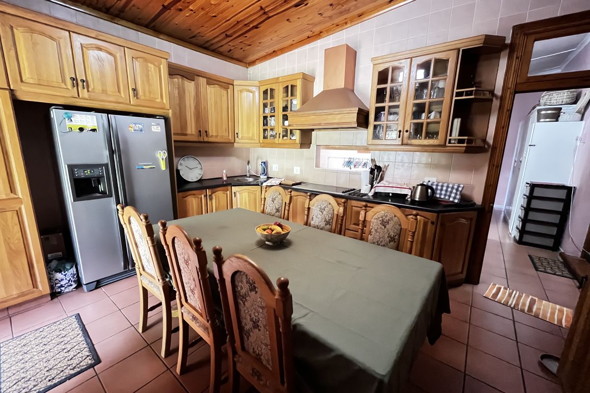 A spacious kitchen featuring timber cabinetry, a built-in extractor fan, tiled flooring, and a timber-paneled ceiling, offering a functional layout for cooking and dining.