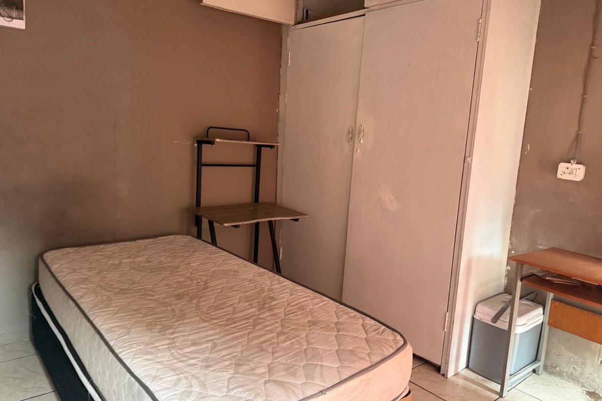 A compact bedroom featuring built-in wardrobe storage and tiled flooring, requiring cosmetic updates to improve the overall finish.