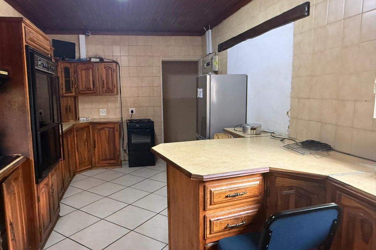 A dated kitchen featuring wooden cabinetry, tiled walls, and a breakfast bar, requiring modernization to improve functionality and aesthetic appeal.